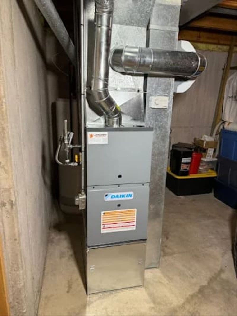Daikin furnace installation in a basement with ductwork and utility features.