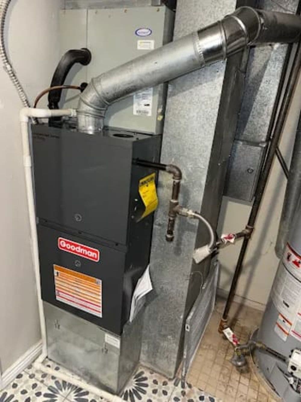 Goodman gas furnace installation in a residential utility room with ductwork.